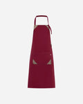 Grembiule unisex bordeaux in poliestere e cotone con pettorina, ampia tasca centrale e dettagli decorativi in alcantara.