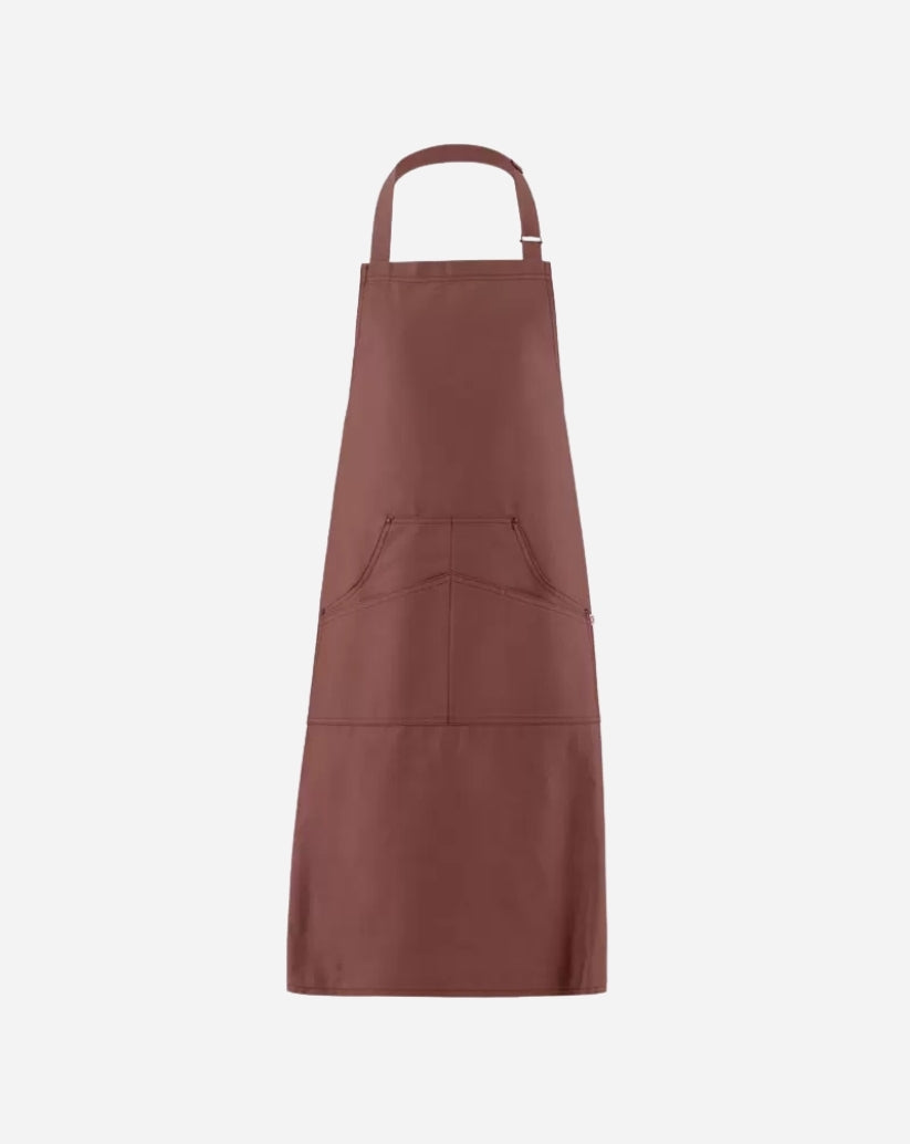 Grembiule a pettorina bruciato in twill di cotone con fibbia regolabile in ottone, tasca centrale e rivetti antichi.
