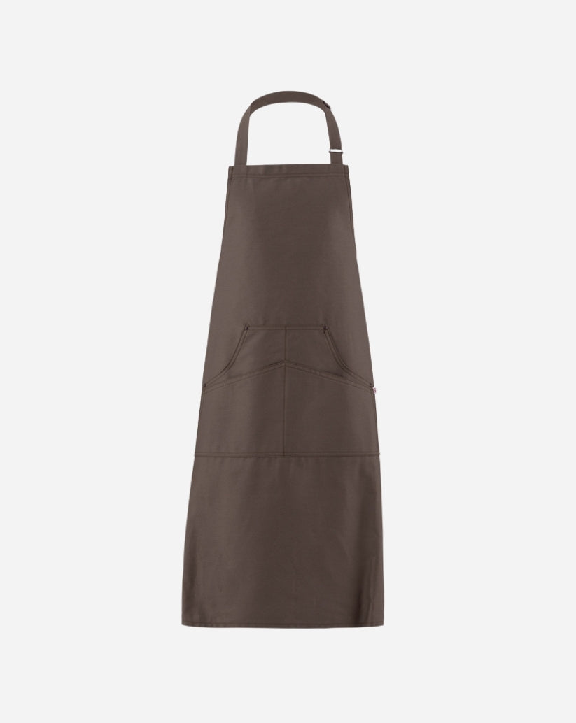 Grembiule a pettorina tortora in twill di cotone con fibbia regolabile in ottone, tasca centrale e rivetti antichi.