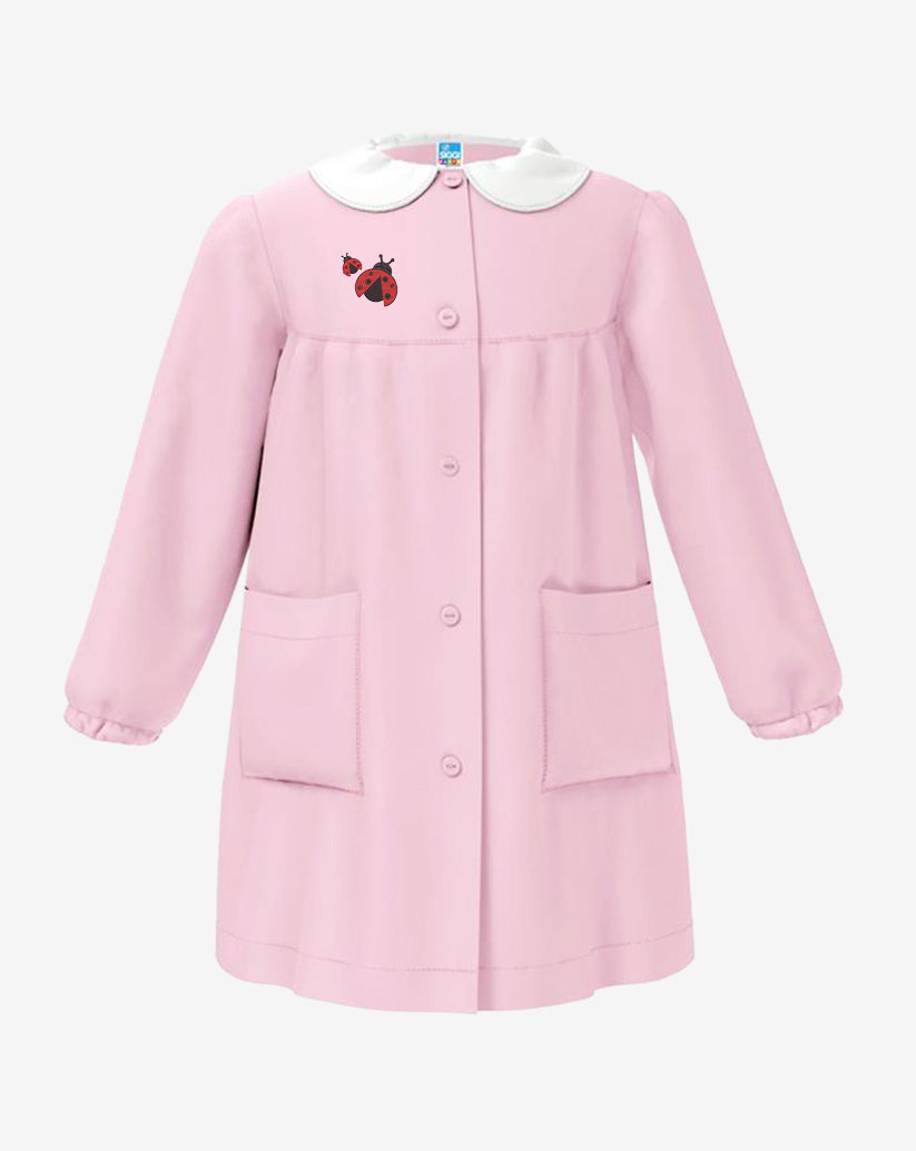 Grembiule da asilo con ricamo  per bambina in  rosa a quadretti, con  colletto bianco a contrasto, allacciatura centrale con bottoni, due  tasche laterali e polsini elasticizzati.