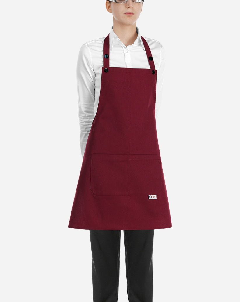 Grembiule a pettorina donna bordeaux in cotone e poliestere con chiusura regolabile al collo, bottoni e due tasche centrali applicate.