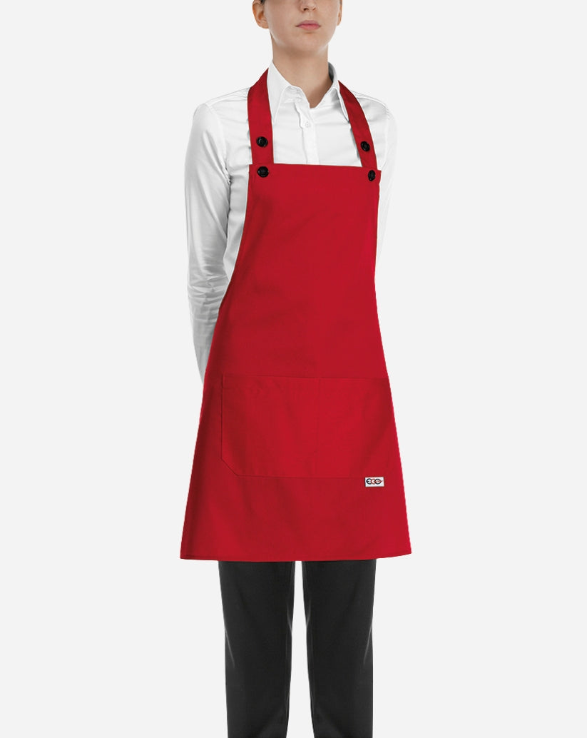 Grembiule a pettorina donna rosso in cotone e poliestere con chiusura regolabile al collo, bottoni e due tasche centrali applicate.